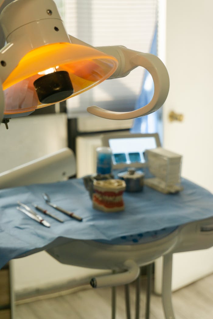 gallery-3 Close-up of a dental examination room featuring instruments and a bright medical lamp.