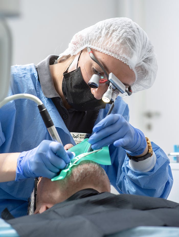 gallery-6 A dentist wearing protective gear performs a dental procedure in a clinic.