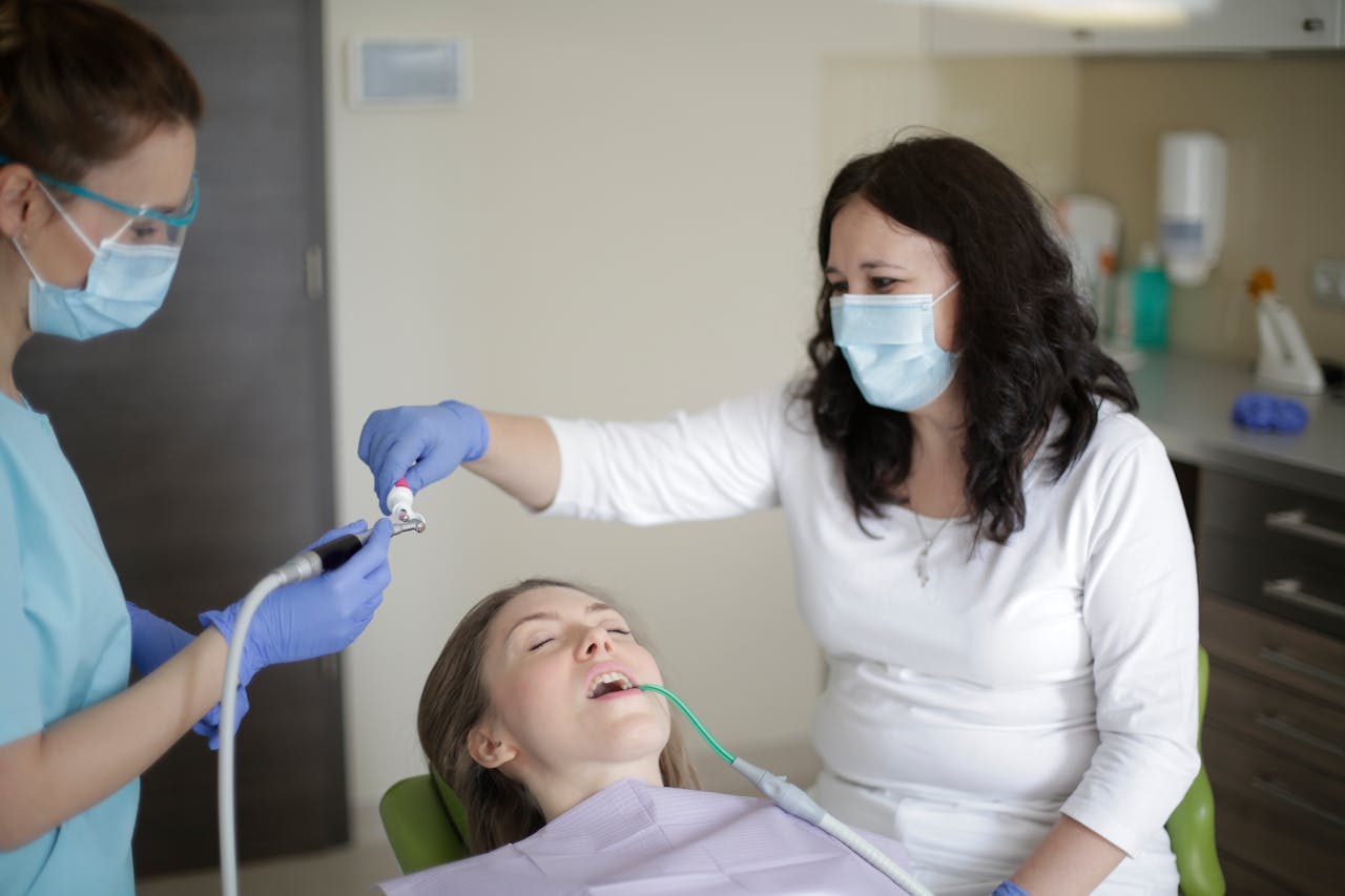 services-02 Middle aged female lying in dental chair with tube suction in mouth while getting professional treatment to fill cavity in tooth in dental clinic